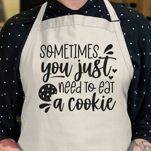 May include: A white apron with black text that reads "Sometimes you just need to eat a cookie". A black and white cookie graphic is included in the text.