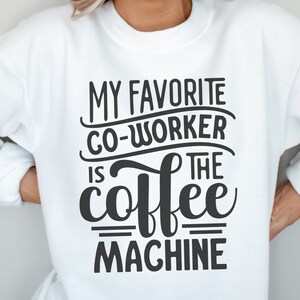 May include: White sweatshirt with the text "MY FAVORITE CO-WORKER IS THE coffee MACHINE" in black. The image also includes the file type abbreviations: SVG, DXF, PNG, and EPS. A pink and blue logo is in the bottom right corner.