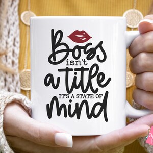 Puede incluir: Taza de cer&aacute;mica blanca con un dise&ntilde;o en negro y rojo. La taza presenta el texto "Ser jefe no es un t&iacute;tulo, es un estado mental".