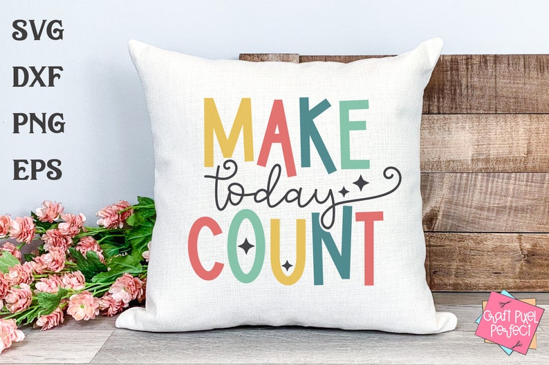 May include: A white pillow with the text "MAKE today COUNT" in colorful letters. The letters are in a rainbow pattern with yellow, red, green, blue, and orange. The text is on a white background with a decorative swirl and stars.