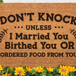 K&ouml;nnte beinhalten: Eine braune Fu&szlig;matte mit dem Text "DON'T KNOCK... UNLESS... I Married You Birthed You OR ORDERED FOOD FROM YOU" in schwarzer Schrift. Die Fu&szlig;matte ist von einem Rand aus gelben Sonnenblumen umgeben.