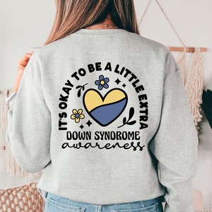 May include: A gray sweatshirt with a yellow and blue heart design and the text "It's okay to be a little extra Down Syndrome awareness".