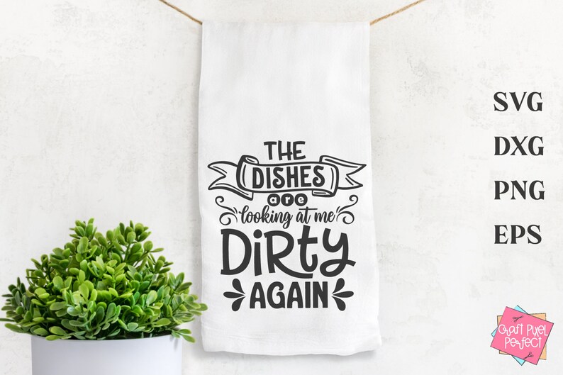 May include: White kitchen towel with the text "THE DISHES are looking at me DIRTY AGAIN" in black. The towel is hanging from a string. A small green plant in a white pot is in the lower left corner.