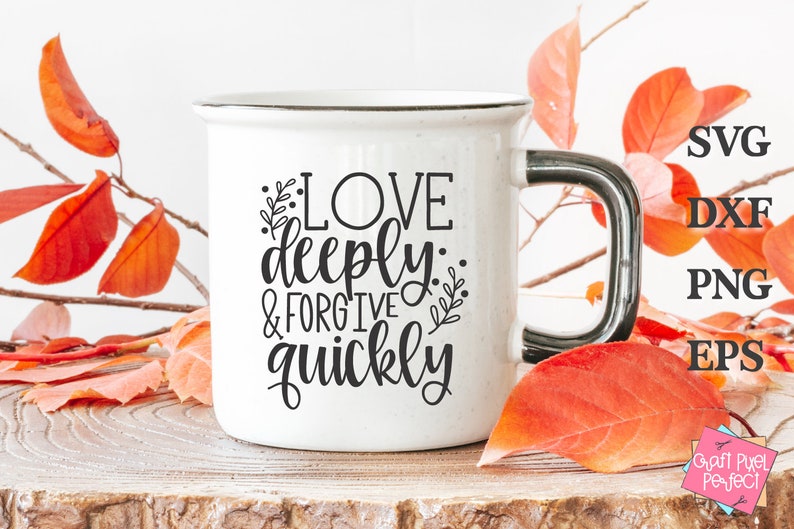May include: White ceramic mug with a black handle. The mug has black text that reads "Love deeply: & forgive quickly". The mug is sitting on a wooden surface with autumn leaves around it.