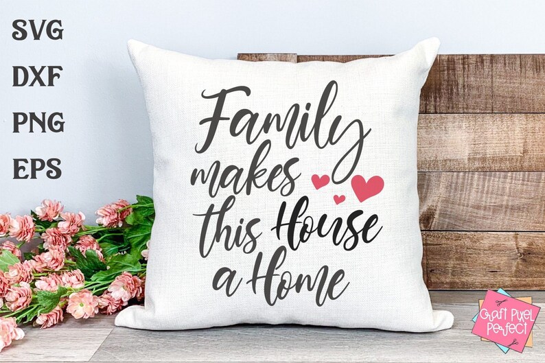 May include: White throw pillow with the text "Family makes this house a home" in black script font. There are three small pink hearts above the word "house".