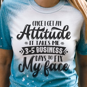 May include: A white t-shirt with a blue tie-dye effect on the sleeves. The shirt has a black graphic that reads "Once I get an Attitude = It takes me = 3-5 Business Days to Fix My Face".