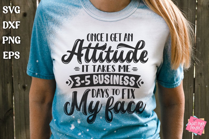May include: A white t-shirt with a blue tie-dye effect on the sleeves. The shirt has a black graphic that reads "Once I get an Attitude = It takes me = 3-5 Business Days to Fix My Face".