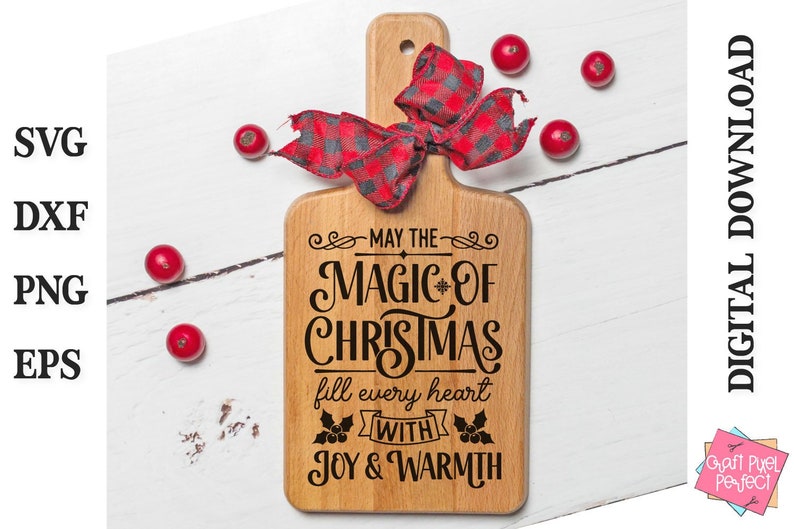 Puede incluir: Una tabla de cortar de madera con una cinta roja y negra de cuadros de b&uacute;falo atada alrededor del mango. La tabla tiene el texto "May the Magic of Christmas fill every heart with Joy & Warmth" impreso en ella.