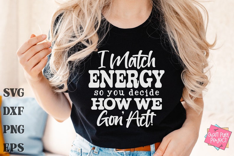 May include: Black t-shirt with the text "I Match ENERGY so you decide HOW WE Gon' Act!" in white. The shirt also has SVG, DXF, PNG, and EPS text on the left side. The shirt is worn by a person with blonde hair.