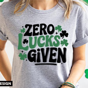 May include: A gray t-shirt with a green shamrock design and the text "Zero Lucks Given".