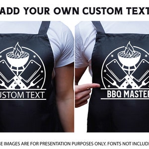 May include: Black apron with a white design of a grill, crossed butcher knives, and forks. The text "BBQ Master" is below the design. The apron is being worn by a person.