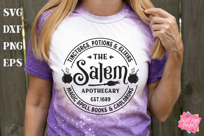 Pu&ograve; includere: Una maglietta bianca con un design circolare nero che dice "The Salem Apothecary Est. 1689" con le parole "Tinctures, Potions & Elixirs" e "Magic Spell Books & Cauldrons" intorno al cerchio.