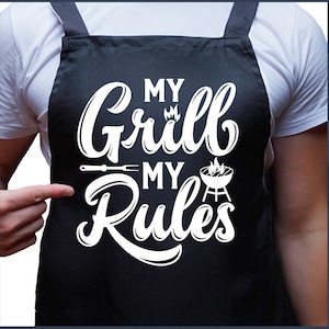 May include: A black apron with white text that reads "My Grill My Rules". The text is in a stylized font and includes a grill and a spatula.