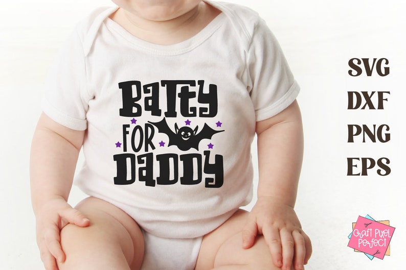 K&ouml;nnte beinhalten: Ein wei&szlig;er Baby-Strampler mit einem schwarzen Aufdruck, der "Batey for Daddy" mit einer schwarzen Fledermaus und lila Sternen sagt.