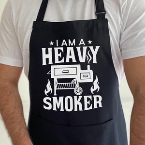 May include: A black apron with white text that reads "I am a Heavy Smoker" and a graphic of a smoker.