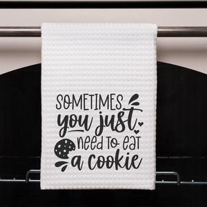 May include: A white kitchen towel with the text "SOMETIMES you just need to eat a cookie" in black lettering. A chocolate chip cookie graphic is included in the text.