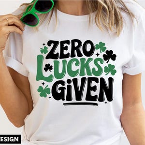 May include: White t-shirt with a black and green graphic that says "Zero Lucks Given". The graphic includes shamrock designs.
