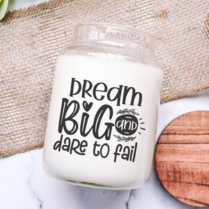 May include: White candle jar with a black design that says "Dream Big and Dare to Fail".