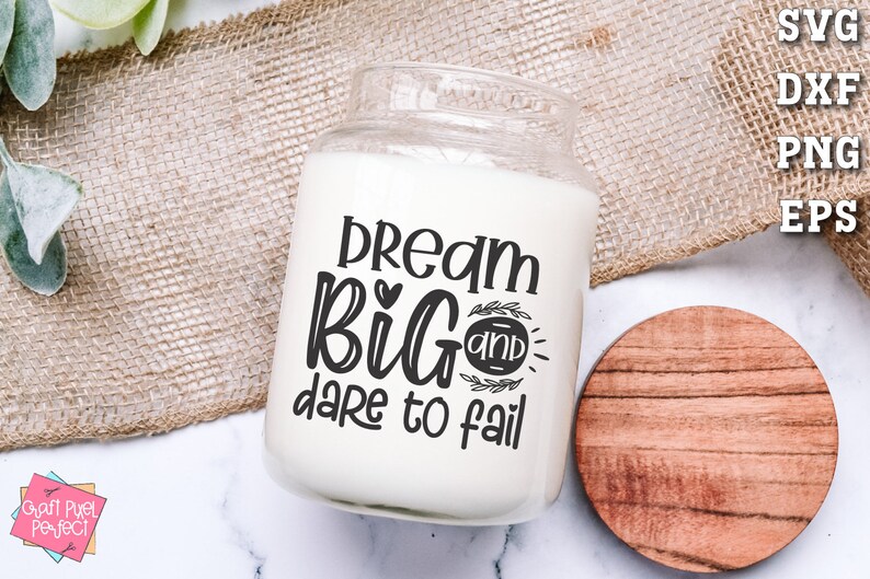May include: White candle jar with a black design that says "Dream Big and Dare to Fail".