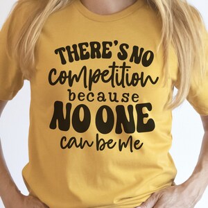 Puede incluir: Una camiseta amarilla con el texto "THERE'S NO competition because NO ONE can be me" en letras negras.
