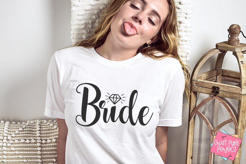 May include: White t-shirt with the word "Bride" in black script with a diamond graphic above the word.