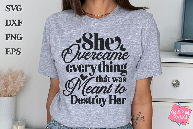 May include: A gray t-shirt with the text "She Overcame everything that was Meant to Destroy Her" printed in black.