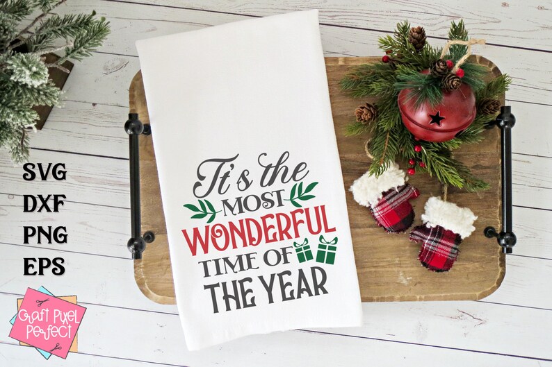May include: White kitchen towel with the text "It's the MOST WONDERFUL TIME OF THE YEAR" in red and gray lettering with green sprigs.