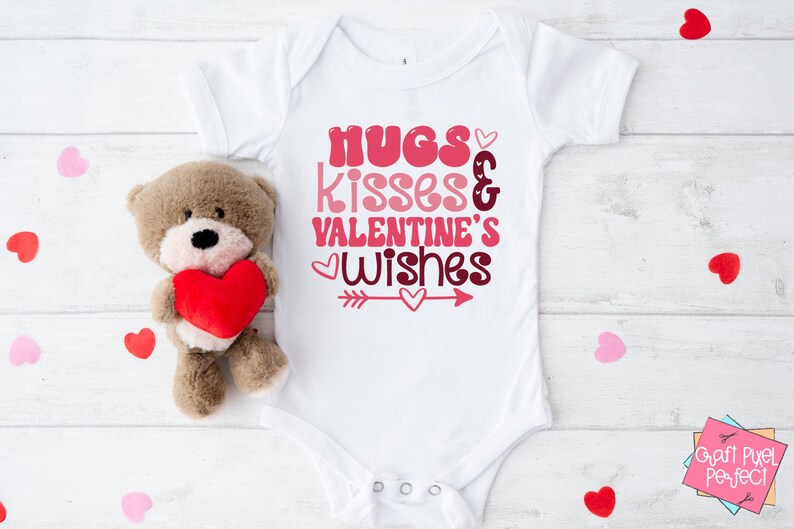 May include: White baby onesie with the text "hugs kisses & valentine's wishes" in pink and red lettering with a pink arrow and hearts.