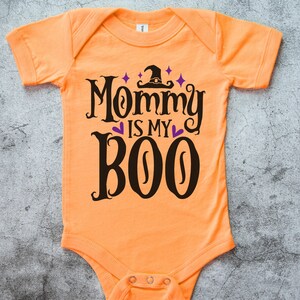 May include: Orange baby onesie with a black and purple design that says "Mommy is my Boo" with a witch's hat above the text.