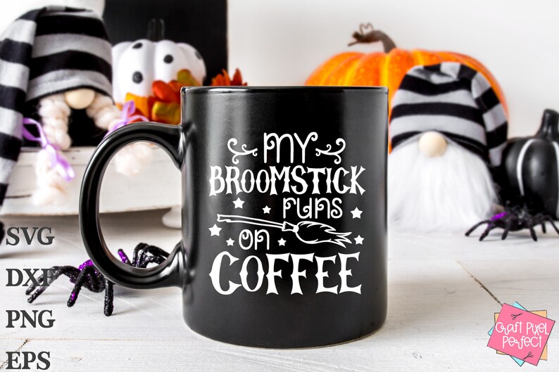 Peut inclure: Une tasse &agrave; caf&eacute; noire avec un motif blanc qui dit "My broomstick runs on coffee" avec un petit balai et des &eacute;toiles. La tasse est pos&eacute;e sur une surface blanche avec une citrouille, des gnomes et des araign&eacute;es en arri&egrave;re-plan.