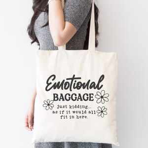 May include: A white tote bag with black text that reads "Emotional Baggage... just kidding... as if it would all fit in here."  The text is surrounded by small black flower designs.