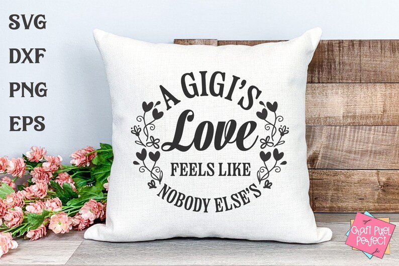 May include: A white cushion with black text that reads "A Gigi's Love Feels Like Nobody Else's" surrounded by a wreath of black hearts and floral designs.