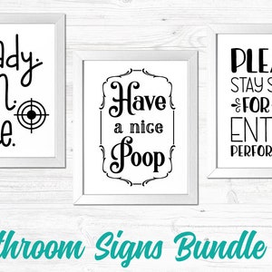 May include: Three white framed bathroom signs with black text. The first sign says "ready aim fire" with a target symbol. The second sign says "Have a nice Poop" with a decorative border. The third sign says "Please stay seated for the entire performance".