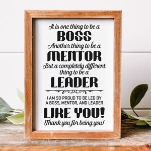 Op de afbeelding: Een ingelijst afdruk met een witte achtergrond en zwarte tekst die luidt: "It is one thing to be a BOSS. Another thing to be a MENTOR. But a completely different thing to be a LEADER. I am so proud to be led by a BOSS, MENTOR, and LEADER LIKE YOU! Thank you for being you!"