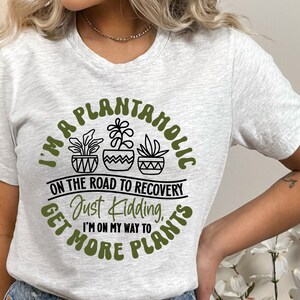 May include: A white t-shirt with a green circle graphic that says "I'm a Plantanholic on the road to recovery. Just kidding, I'm on my way to get more plants."