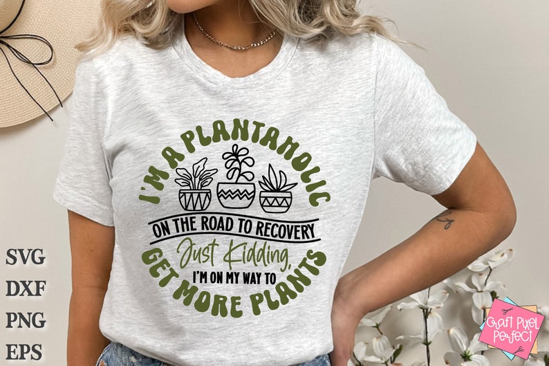 May include: A white t-shirt with a green circle graphic that says "I'm a Plantanholic on the road to recovery. Just kidding, I'm on my way to get more plants."