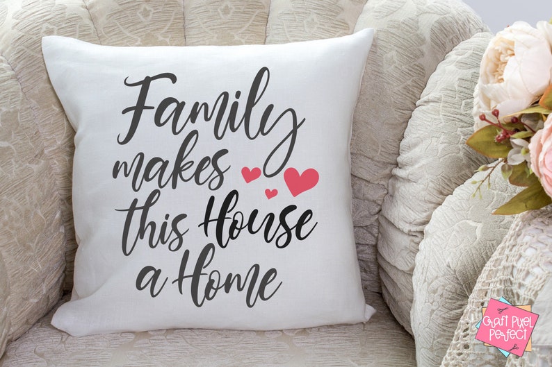 May include: White throw pillow with black text that reads "Family makes this house a home" with pink hearts.