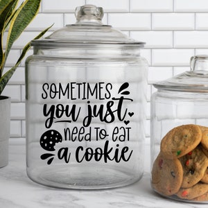 May include: A glass cookie jar with a black vinyl decal that reads "Sometimes you just need to eat a cookie". The jar is filled with chocolate chip cookies.