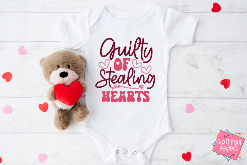 May include: White baby onesie with the text "Guilty of Stealing Hearts" in pink and maroon lettering with pink hearts and an arrow.