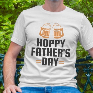 May include: White t-shirt with a graphic of two beer mugs and the text "Hoppy Father's Day".