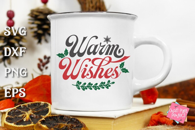 May include: White ceramic mug with a black rim and handle. The mug has a red and black design that says "Warm Wishes" with a snowflake and green holly leaves.