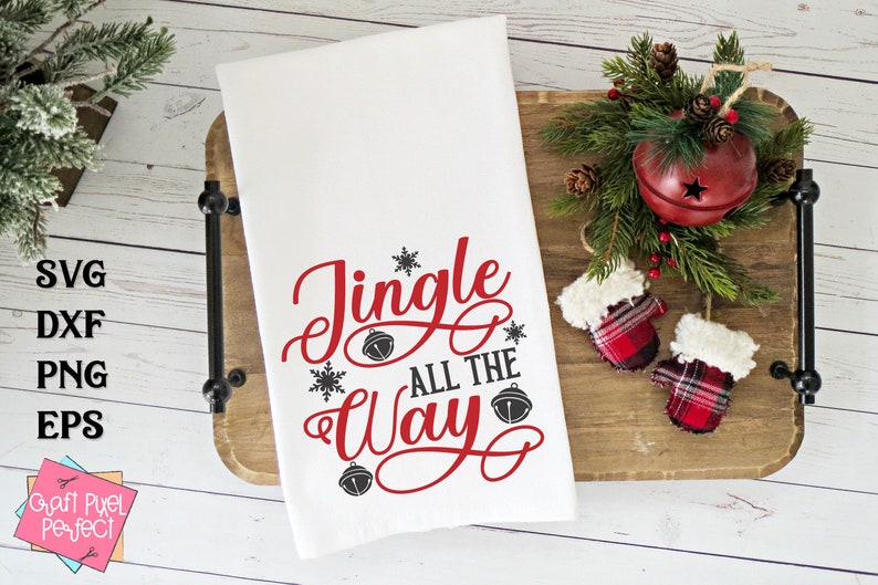 May include: White kitchen towel with the text "Jingle All The Way" in red cursive lettering with black snowflake and bell accents.