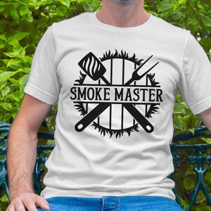 May include: White t-shirt with a black graphic design of a grill with crossed grilling tools and the text "Smoke Master".