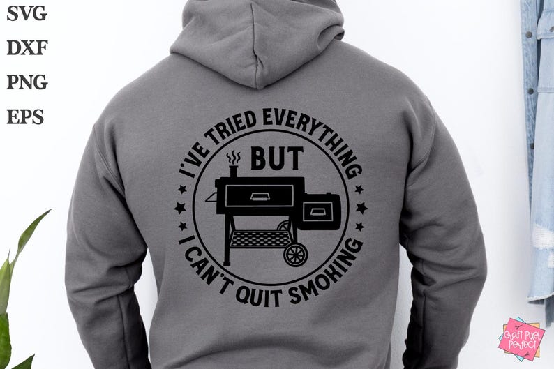 May include: A gray hoodie with a black circle graphic on the back. The graphic features a smoker with the text "I've tried everything but I can't quit smoking".