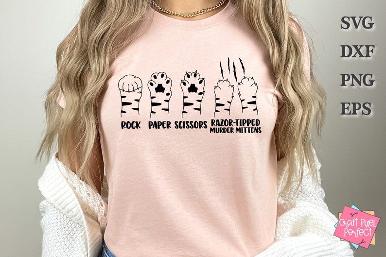 May include: A pink t-shirt with a graphic of a cat paw print in the shape of a rock, paper, scissors hand gesture. The text reads "Rock Paper Scissors Razor-Tipped Murder Mittens".