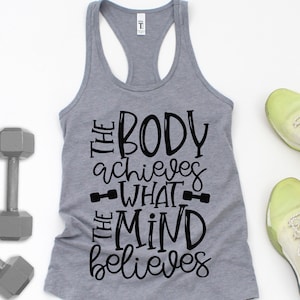 Puede incluir: Un top gris sin mangas con el texto "The body achieves what the mind believes" en letras negras. El texto est&aacute; estilizado con un gr&aacute;fico de mancuerna a cada lado de la palabra "what".