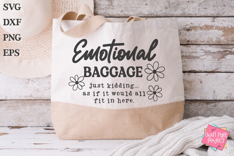 May include: A white canvas tote bag with brown handles. The bag has black text that reads "Emotional Baggage just kidding... as if it would all fit in here." with a daisy design on either side of the text.