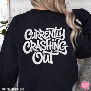 May include: A black sweatshirt with the white text "Currently Crashing Out" on the back. The sweatshirt is a digital download. The design is in a cursive font.