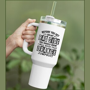 May include: White travel mug with a black handle and a black graphic that reads "Before you get on my bad side you should know I will rock that orange jumpsuit".