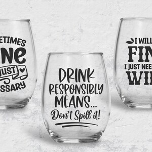 May include: Three clear glass wine glasses with black vinyl lettering. The glasses have the following text: "Sometimes wine is just necessary", "Drink responsibly means... Don't spill it!" and "I will be fine I just need some wine".